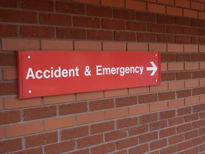 a red sign on a brick wall that leads the way to "accident & emergency"